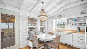 A kitchen with white cabinetry, a round dining table, wicker chairs, and a hanging light fixture. - Waterfront Cottage Near Beach Access (Cape San Blas)