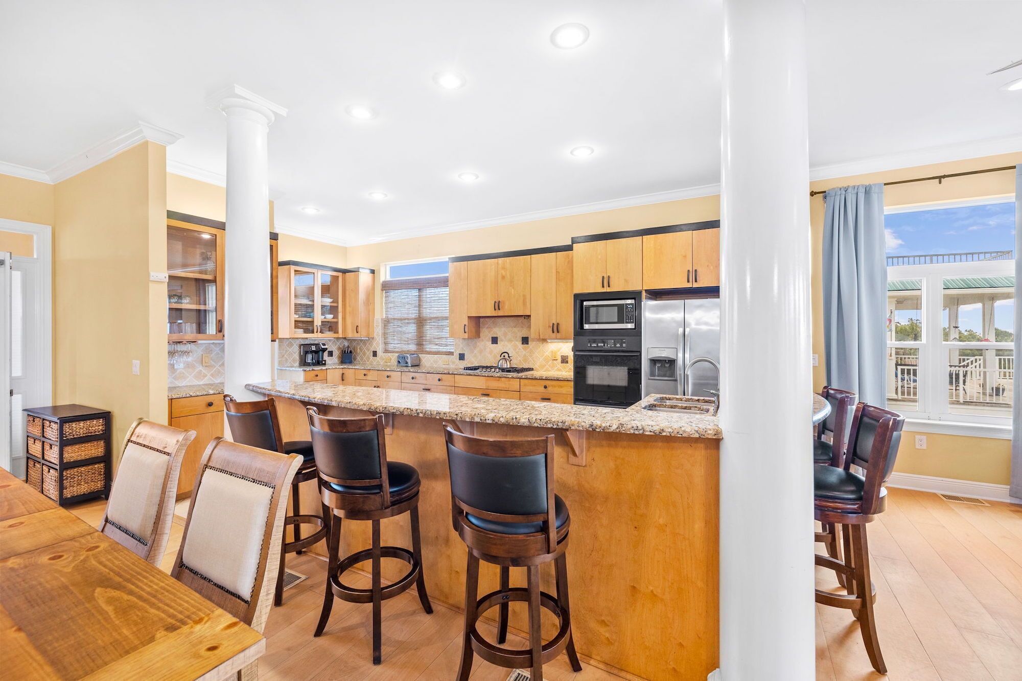 A spacious kitchen with a central island, bar stools, and a dining table.