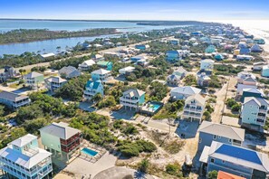 Vista aérea de uma área residencial costeira, com casas, uma praia e um corpo de água.