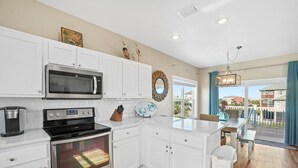 A modern kitchen with white cabinetry, stainless steel appliances, and a view to the outside.