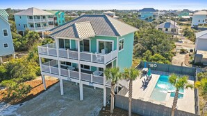 A two-story house with a balcony, a swimming pool, and a view of neighboring houses.