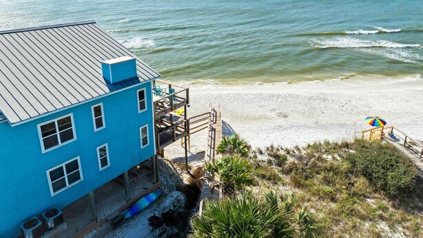 A beachfront property with a blue building, a sandy beach, and a view of the ocean.