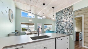 A kitchen with a large island, white cabinetry, and a backsplash with blue and white tiles.