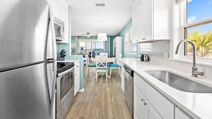 A modern kitchen with stainless steel appliances, a dining area with a table and chairs, and a view of the outdoors through a window. - Cozy Duplex Near Community Beach Access (Port St. Joe)