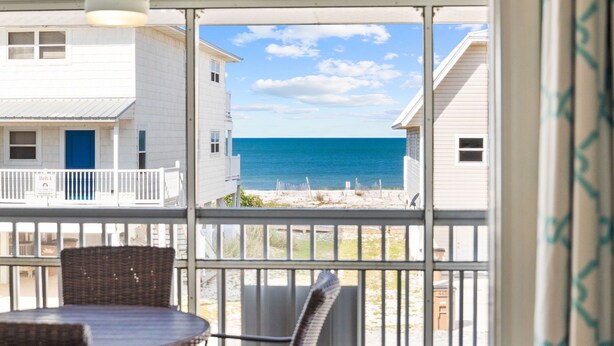 A balcony with a view of the ocean, white buildings, and a blue door. - Cozy Duplex Near Community Beach Access (Port St. Joe)