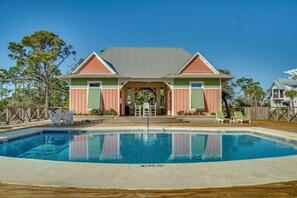 A pool with a clear blue water surface, a covered area with a roof, and a building with a red and green facade.