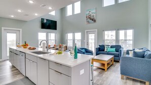 A spacious living area with a kitchen island, a dining table, and a large window. - Beach Retreat w/Pool and Foosball (Port St. Joe)