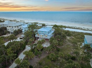 A coastal property with multiple buildings, a beachfront, and a variety of vegetation.