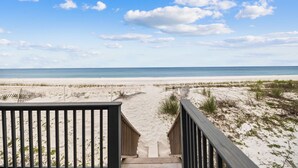 A wooden pathway leading to a beach with a clear sky.