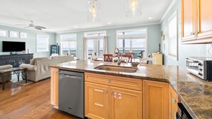 A spacious kitchen with a central island, wooden cabinets, a built-in dishwasher, and a stainless steel oven.