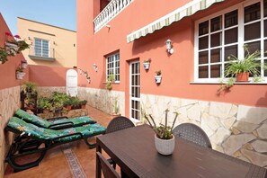 A patio with lounge chairs, a table, and potted plants.