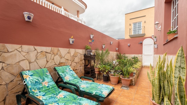 A patio with two lounge chairs, potted plants, and a stone wall. - Holiday Home Casa Matyas close to the Beach with Garden & Wi-Fi (Icod de los vinos)