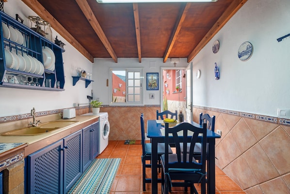A kitchen with a dining table, chairs, a washing machine, and a sink.