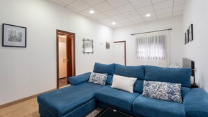 A living room with a blue sectional sofa, a black coffee table, and a door leading to another room. - Holiday Home Casa Matyas close to the Beach with Garden & Wi-Fi (Icod de los vinos)