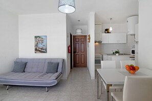 A compact living space with a sofa, dining table, and kitchenette.