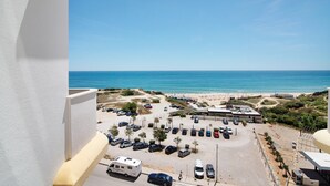 Ein Parkplatz mit Fahrzeugen, einem Strand und blauem Himmel.
