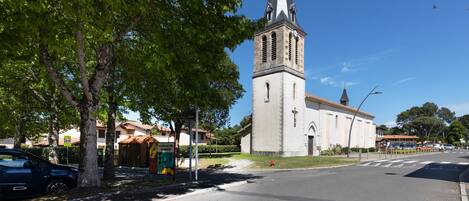 A church with a tall steeple, a cross at the top, and a clear blue sky.