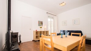 Un comedor con una mesa y sillas de madera, un televisor y una estantería.