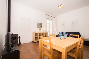 Un comedor con una mesa y sillas de madera, un televisor y una estantería.