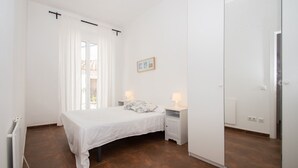Un dormitorio con cama, mesitas de noche, radiador y puerta corrediza.
