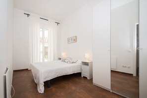 Un dormitorio con cama, mesitas de noche, radiador y puerta corrediza.