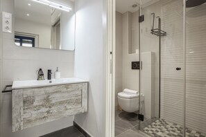 A modern bathroom with a white vanity, a glass shower enclosure, and a visible toilet. - Spectacular designer loft just five minutes' walk from the beach (Canet de Mar)