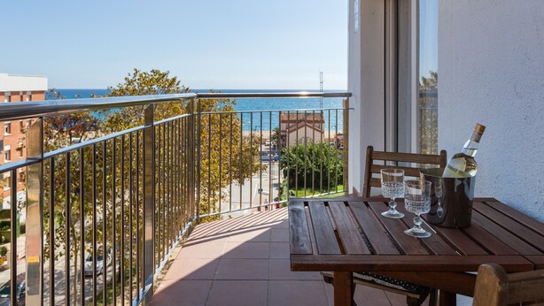 A balcony with a table, two chairs, a bottle of champagne, and two glasses.