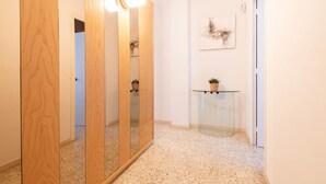 A hallway with a wooden wardrobe, a glass table with a plant, and a framed picture on the wall.