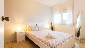 A bedroom with a bed, bedside tables, a mirror, and a window with curtains.