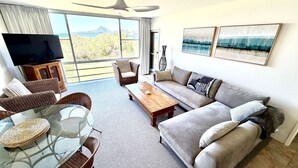 Un salón amplio con balcón, un sofá, una mesa de centro y un televisor.