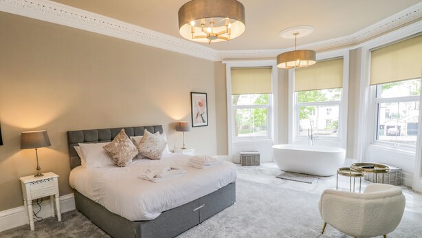 Een moderne slaapkamer met een groot bed, een badkuip en een stoel.