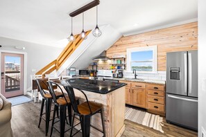 A modern kitchen with a central island, wooden cabinetry, and a stainless steel refrigerator.