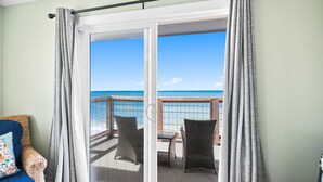 A room with a sliding glass door leading to a balcony with wicker furniture and a view of the ocean. - Gulf Front | Outdoor Shower | Dogs Allowed (Port St. Joe)