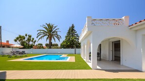 Ein modernes Haus mit Swimmingpool, Terrasse und weißer Fassade.