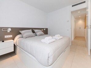A modern bedroom with a large bed, bedside tables, and a walk-in closet.