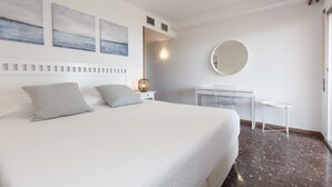 A modern hotel room with a large bed, a desk, and a round mirror. - Spectacular Apartment in the heart of Paseo Jaime I - UHC ANAGABU (Only families) (Salou)