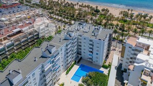 A high-rise hotel with a rooftop pool, beachfront views, and a palm-lined promenade. - Spectacular Apartment in the heart of Paseo Jaime I - UHC ANAGABU (Only families) (Salou)