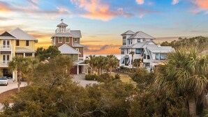 A coastal residential area with multiple houses featuring modern architecture, surrounded by lush greenery and palm trees.