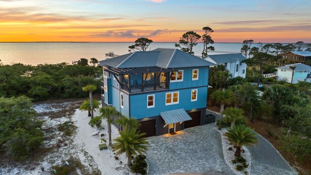 A two-story house with a balcony, surrounded by trees and a beach view. - Bay Front Escape w/ Dock and Gulf Views (Port St Joe)