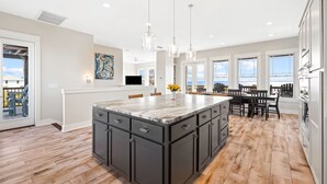 A spacious kitchen with a large island, wooden flooring, and a view of the ocean. - Bay Front Escape w/ Dock and Gulf Views (Port St Joe)