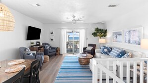 Un salon moderne comprenant un coin repas, un ventilateur de plafond, un téléviseur et une vue sur l’extérieur.