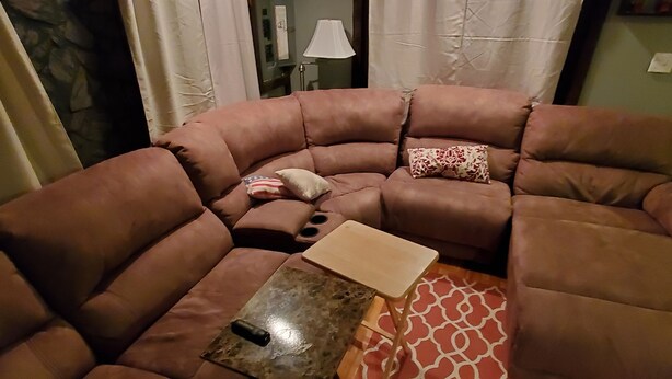 A living room with a brown leather sofa, a small wooden table, and a patterned rug.