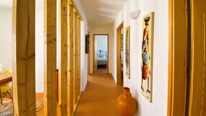 Ein Korridor mit Holztüren, Fliesenboden und Kunstwerken an den Wänden.
