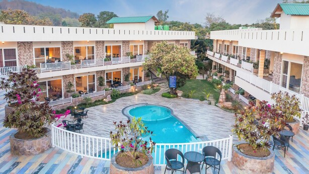 Un hôtel doté d’une piscine, entourée d’espaces de détente en plein air et de plantes en pot.