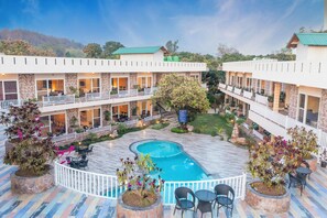 A hotel with a swimming pool surrounded by outdoor seating areas and potted plants. - Vow Resorts And Spa (Kaladhungi)