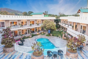 A hotel with a swimming pool surrounded by outdoor seating areas and potted plants.
