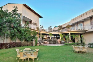 A hotel with a courtyard featuring outdoor seating, a stone fountain, and lush greenery.
