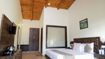 Un dormitorio con techo de madera, un ventanal grande, una cama con ropa de cama blanca, un aparador de madera y un televisor en la pared.