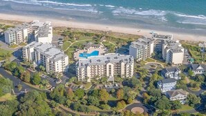 Vista aèria d'un complex hoteler a la costa, amb diversos edificis, una piscina i una platja al fons.