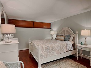 Une chambre à coucher avec un lit, deux tables de chevet, un miroir et un plafond en bois.